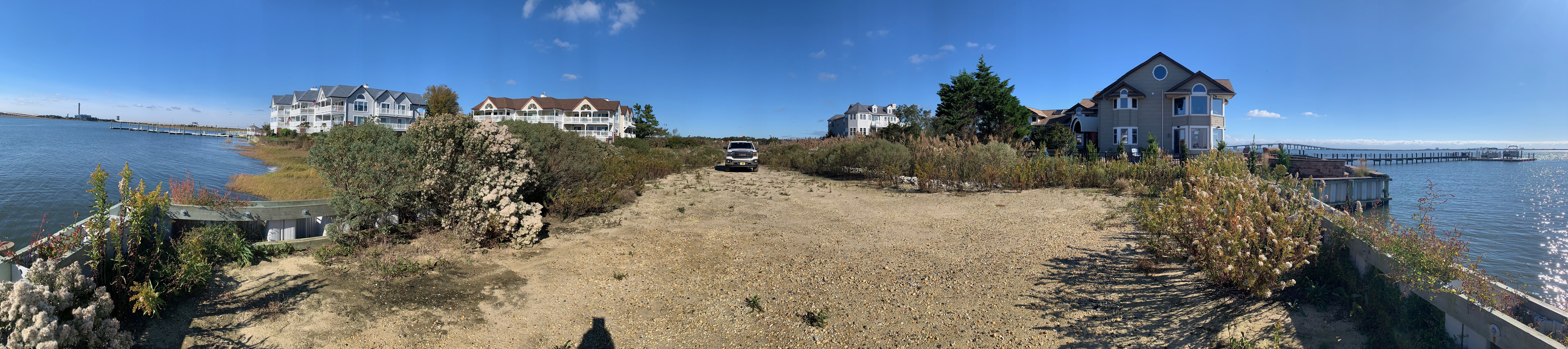 Panoramic ground-level view from the bulkhead at 104 Broadway, looking back across the buildable pad toward Broadway Avenue.